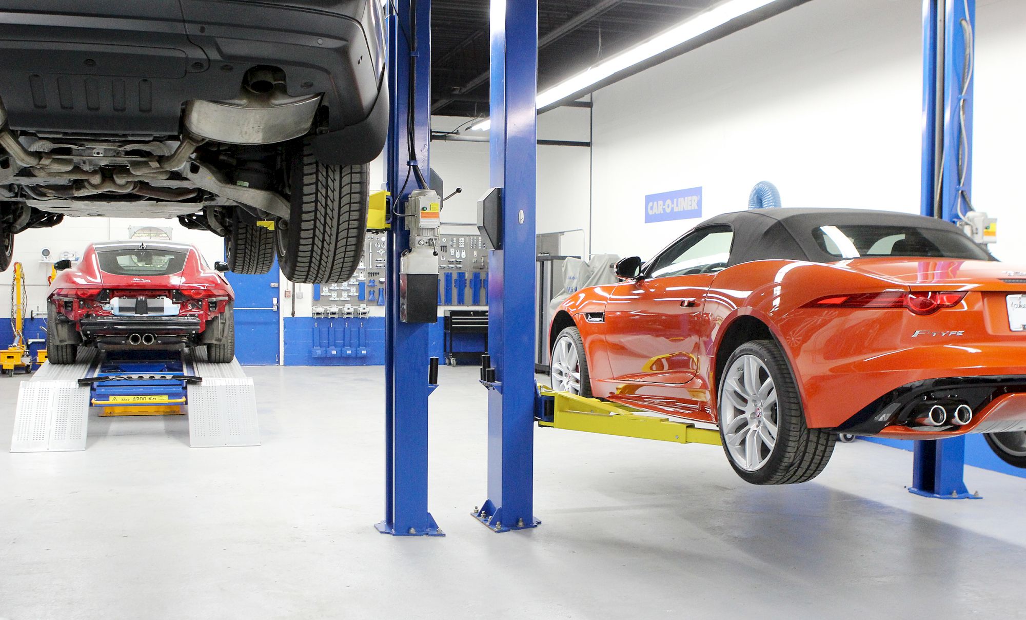 A car repair shop with two cars on hydraulic lifts and a garage work area is visible.
