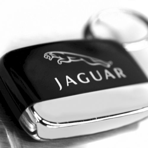 A Jaguar car key fob is displayed, featuring the brand's logo against a sleek black surface.
